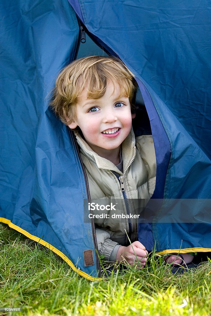 Giovane ragazzo guardando fuori la prima volta in campeggio Tenda - Foto stock royalty-free di Lupetti scout