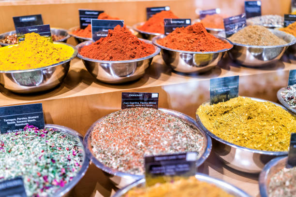 Many spices on display in bowls trays filled with herbs, signs, madras curry, paprika, turmeric, chimichurri, tarragon, rosebuds, mixes