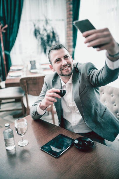 Smiling Business  Man With Braids Make Selfie While Drinking Coffee in a Restaurant