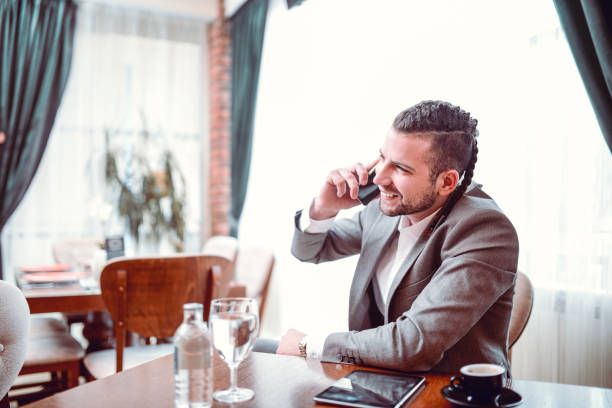 istock Smiling Business  Man With Braids Make Important Phone Call in Restaurant 925508132