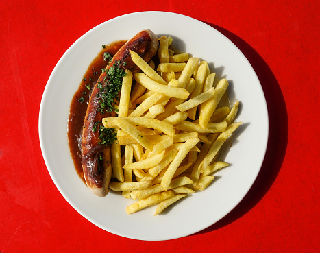 Dinner plate with a bratwurst and fries
