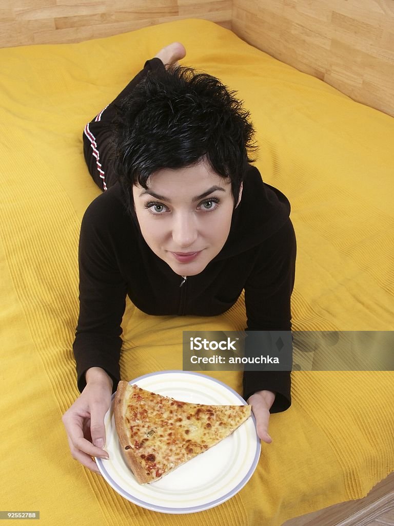 Mujer joven con la pizza en la cama - Foto de stock de 20 a 29 años libre de derechos