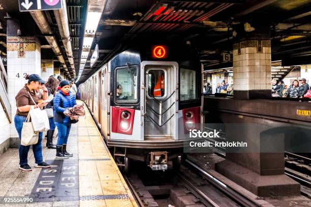 People Waiting In Underground Transit Empty Large Platform In Nyc Subway Station Railroad Tracks Woman Eating Incoming Train Stock Photo - Download Image Now