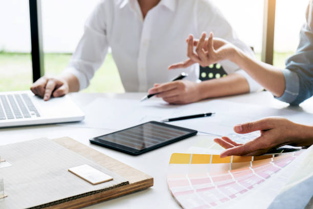 istock Two interior design or graphic designer at work on project of architecture drawing with work tools and color swatches, colour chart, color samples for selection, renovation and technology concept 925561282