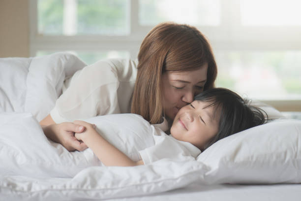 istock mother  kissing her son on white bed 925565192