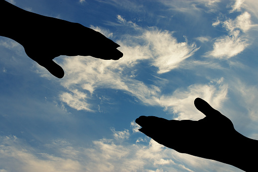 silhouette of helping hand on sky background