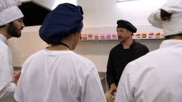 Teacher chef teaching his students about different ingredientes and then smelling a garlic that a student gives him approving that it is fine