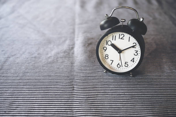 istock Closeup image of a black alarm clock on the table with blur background 925578740
