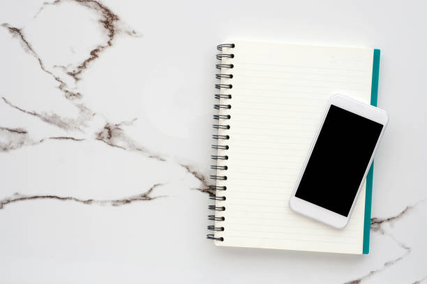 istock Smart phone with blank screen on blank notebook paper background, mock up, flat lay 925590520