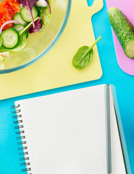 istock Notepad with fresh biodynamic ingredients for cooking summer salad on blue background, top view. Healthy food background 925596924