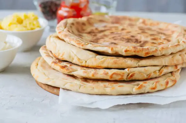 Mashed potato and sheep cheese filling flatbread on a white stone background.