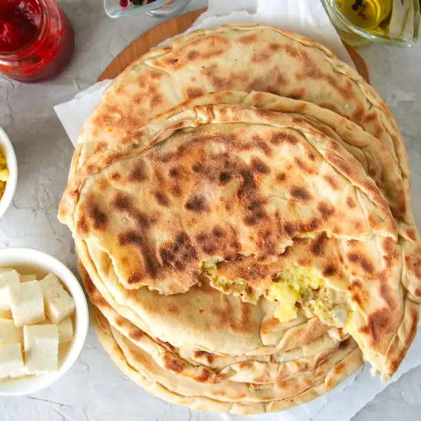 Mashed potato and sheep cheese filling flatbread on a white stone background.