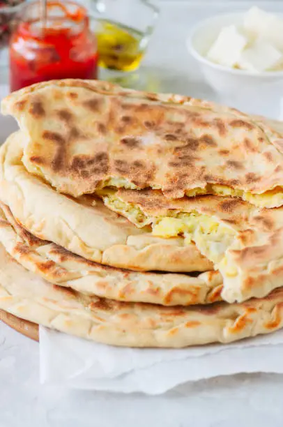 Mashed potato and sheep cheese filling flatbread on a white stone background.