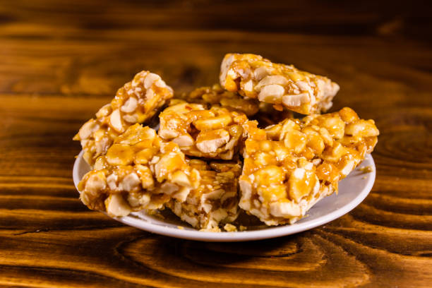 istock Ceramic plate with peanut brittles on wooden table. 925608482