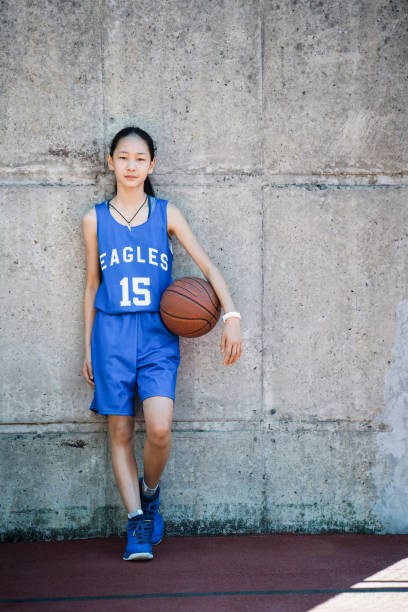 joueur de basket féminin debout avec boule - child basketball uniform sports uniform photos et images de collection