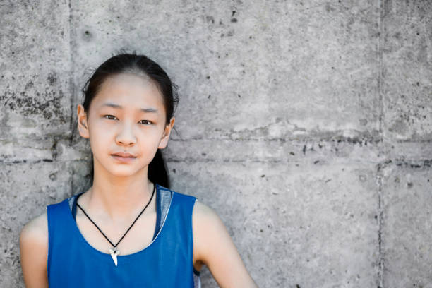 Portrait of confident female basketball player. Girl is standing against wall. She is wearing sports jersey.