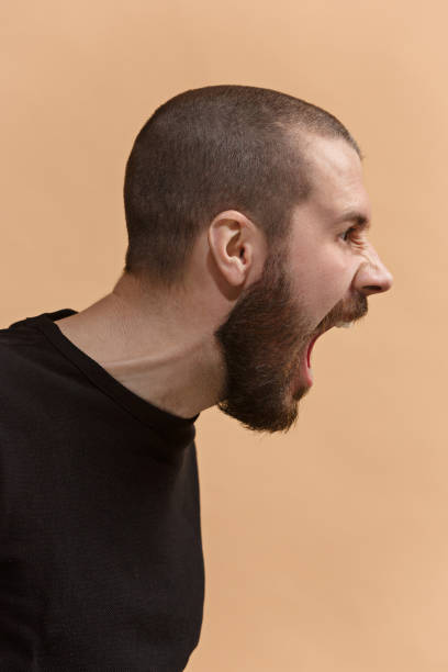 istock The young emotional angry man screaming on pastel studio background 925631064