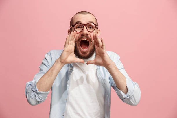 istock Isolated on pink young casual man shouting at studio 925632286