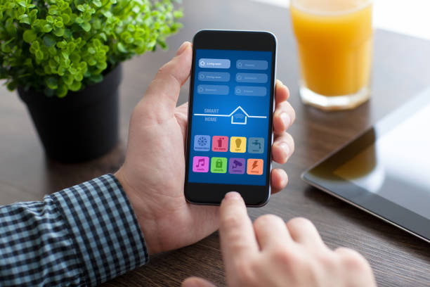 istock man holding phone with app smart home over desk 925633086