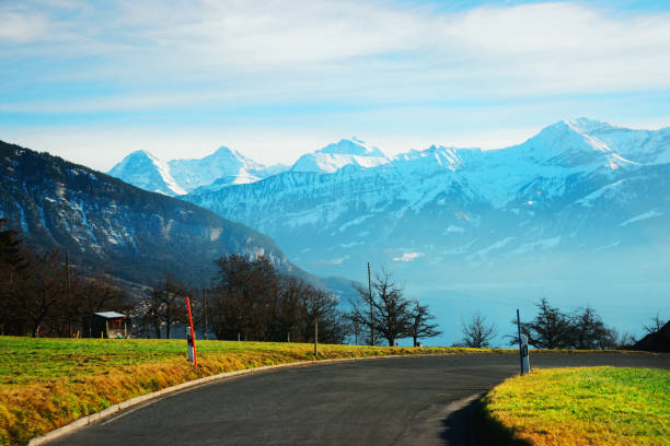 Road at Sigrilwil village Swiss Alps mountains Thun lake Road at Sigrilwil village in front of Swiss Alps mountains and Thun lake, Switzerland in winter thun interlaken winter switzerland stock pictures, royalty-free photos & images