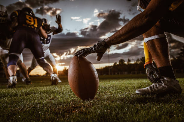 Ready, set, kick off! Unrecognizable American football player preparing a ball for kick off on a playing field. sports field photos stock pictures, royalty-free photos & images