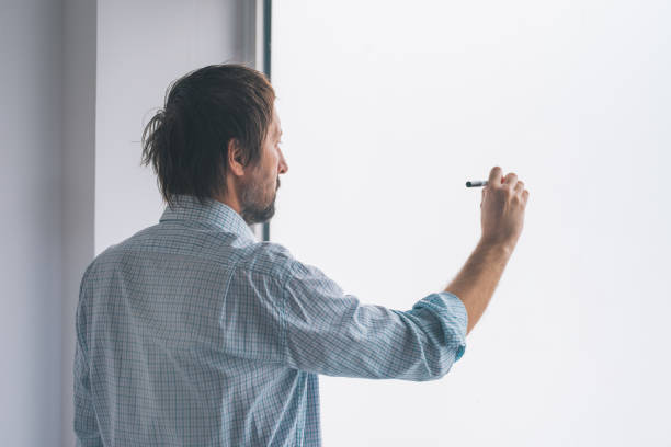 istock Businessman in office writing on whiteboard 925640132
