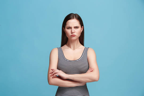 istock The serious woman standing and looking at camera against blue background 925640708