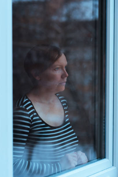 istock Depressed woman standing by the window 925640858