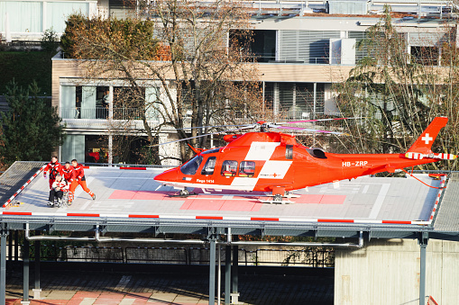 Thun, Switzerland - January 1, 2014: Helicopter and patient at hospital roof in Thun City. Thun is a city in the canton of Bern in Switzerland. There is a view of Bernese Alps.