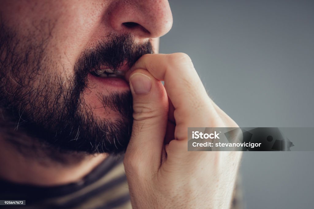 Nervous male biting fingernails Close up of nervous male biting fingernails Nail Biting Stock Photo