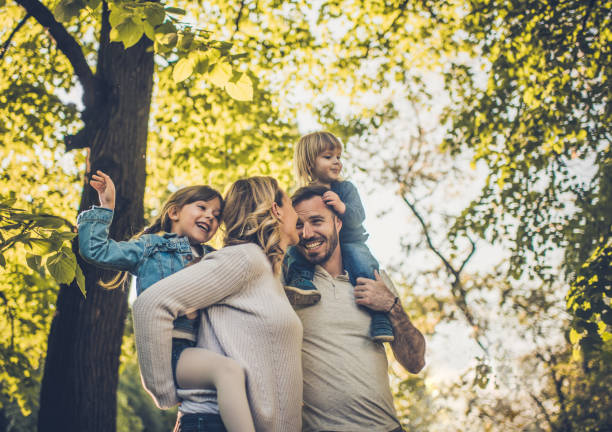 Below view of carefree family having fun in spring day. Low angle view of happy family enjoying in spring day at the park. piggyback photos stock pictures, royalty-free photos & images
