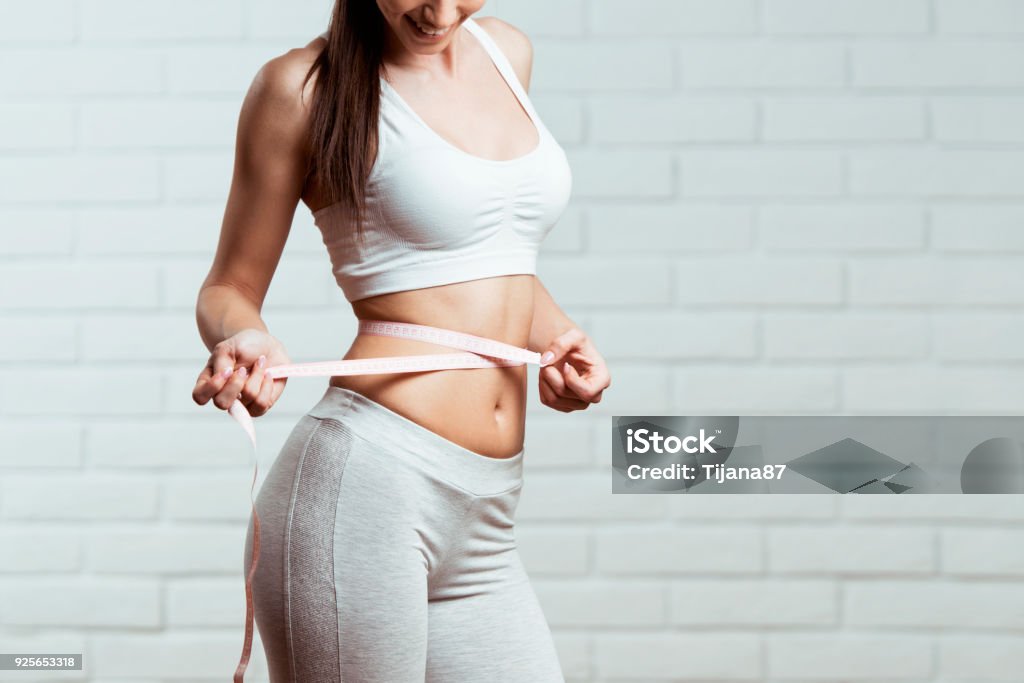 Beautiful, fit, young woman measuring her waist Dieting Stock Photo