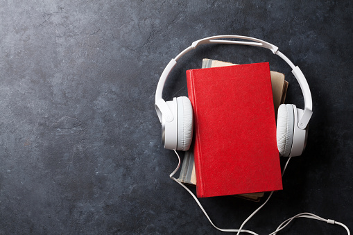 Audio book concept. Headphones and books over stone table. Top view with space for your text