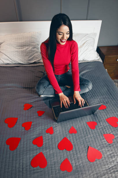 istock Beautiful young woman surrounded with red hearts, using a laptop 925653834