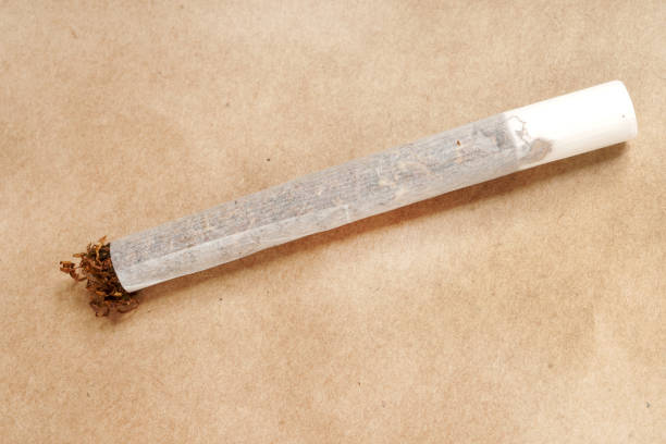 istock Hand rolled cigarette with filter close-up on wrapping paper background 925660230