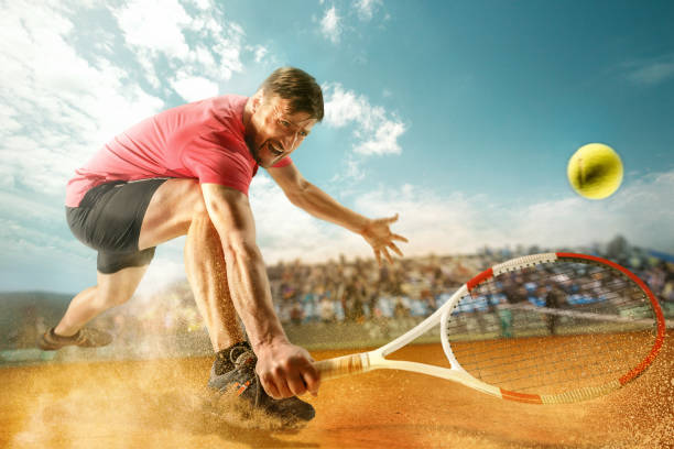 один прыжки игрок, кавказский подходят человек, играя в теннис на земляном корте со зрителями - tennis serving men court стоковые фото и изображения