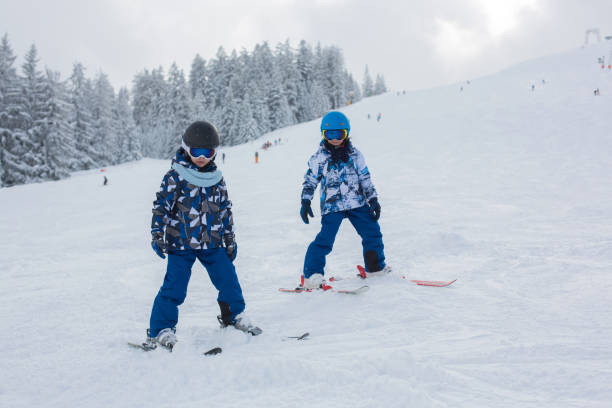 cute preschool children, skiing in austrian winter resort on a clear day, wintertime - czech republic ski winter skiing imagens e fotografias de stock