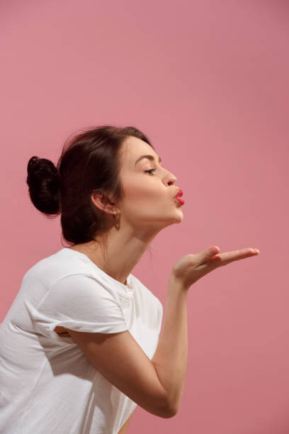 Portrait of attractive cute girl with bright makeup with kiss isolated over pink background I kiss you. Portrait of attractive woman with kiss on lips. Pink studio. Beautiful female portrait. Young happy emotional funny woman looking at camera. Human facial emotions concept. Profile blowing a kiss stock pictures, royalty-free photos & images