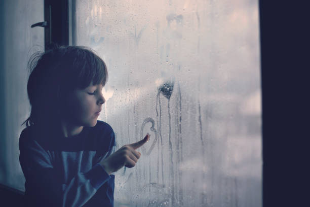 garotinho, deixando impressões digitais e desenho corações em uma janela - sadness child little boys loneliness - fotografias e filmes do acervo