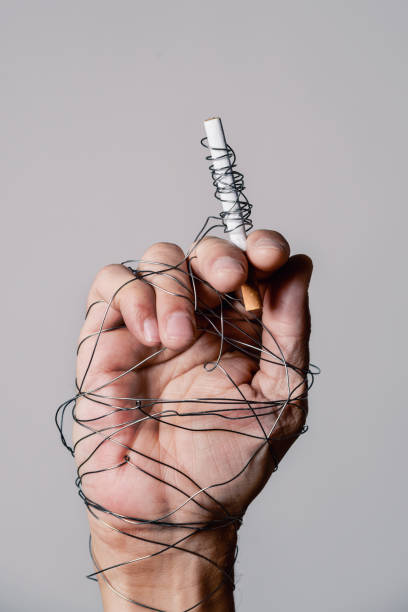 istock man hand and cigarette tied with wire 925669456