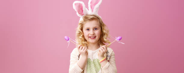 istock smiling girl isolated on pink with purple handmade Easter eggs 925671702