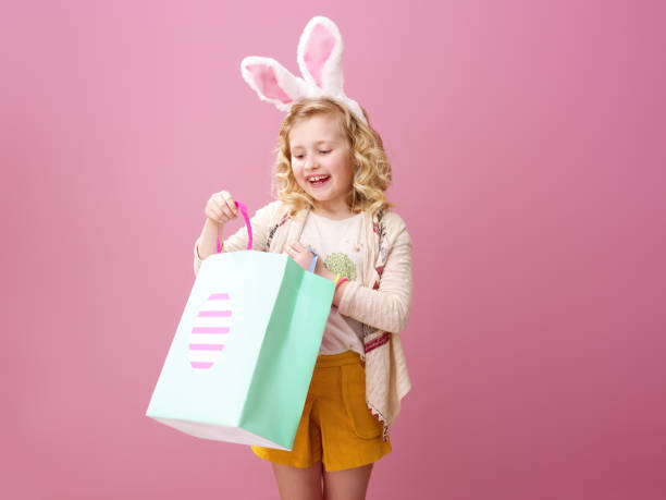 istock smiling girl on pink background looking at Easter shopping bag 925671792