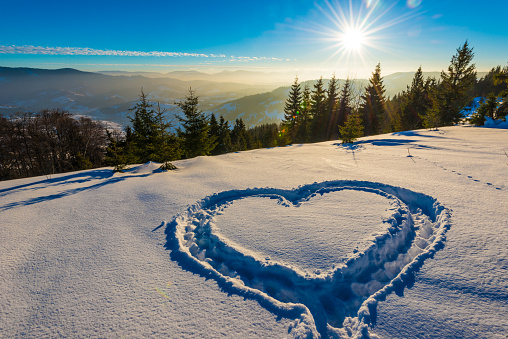 Winter mountain landscape with snowly fir. Winter mountain heart sign on a sunny day.