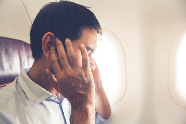 Male passenger having ear pop on the airplane Male passenger having ear pop on the airplane while taking off (or landing) landing touching down stock pictures, royalty-free photos & images