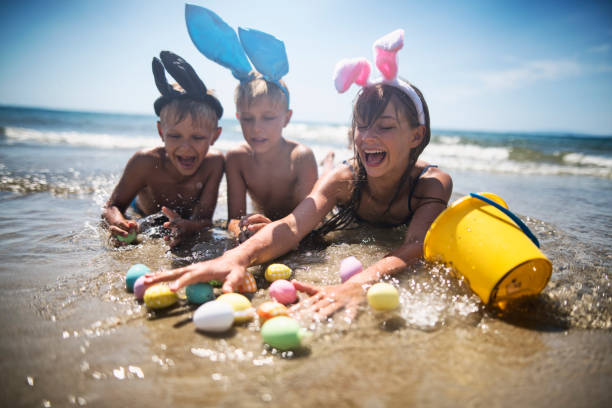 Kids playing in sea during Easter It's Easter on the beach! Kids aged 8 and 11 are lying in sea water and having fun wearing easter bunny ears. Kids are catching easter eggs in water.
girls laying on beach stock pictures, royalty-free photos & images