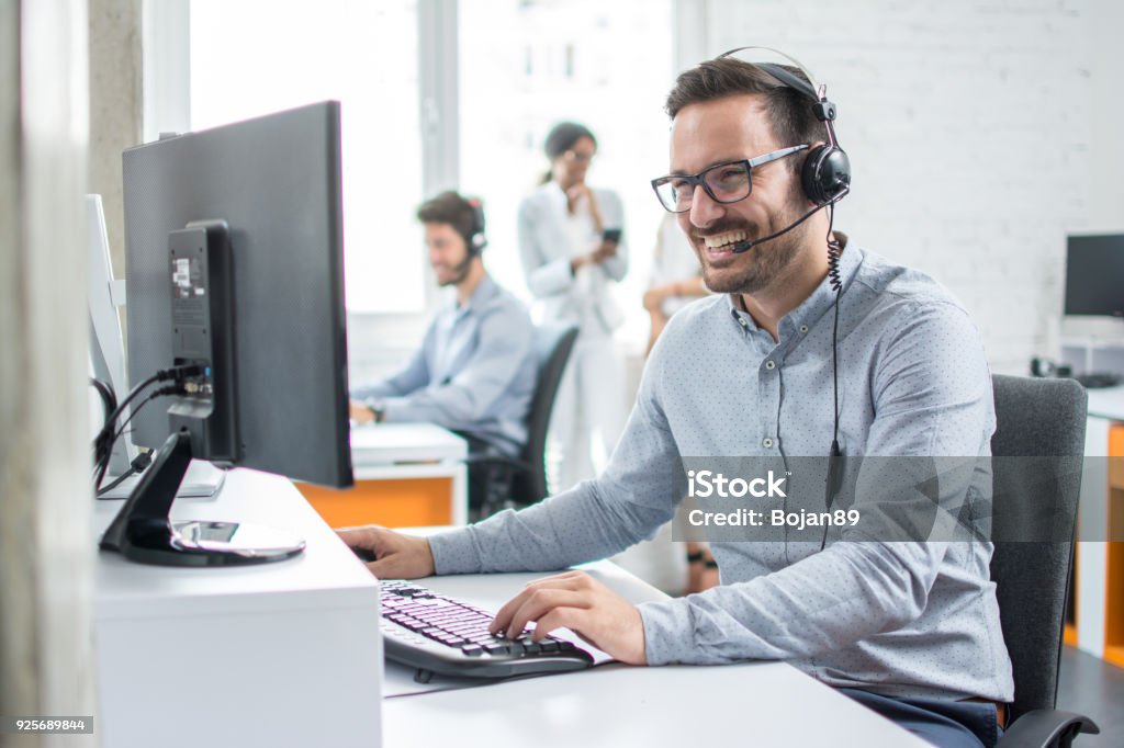 Smiling customer support operator with hands-free headset working in the office. Support Stock Photo