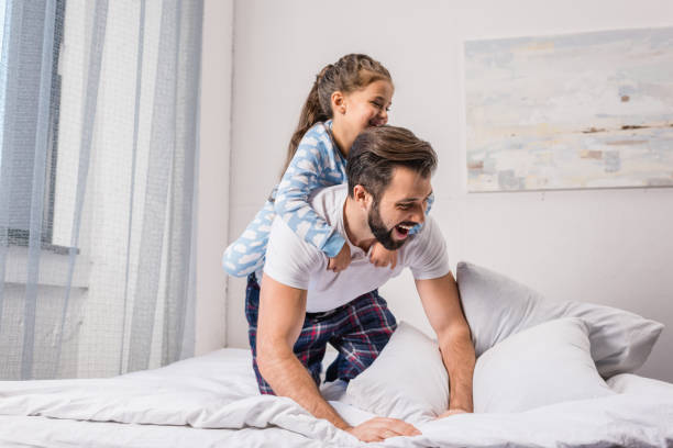 istock father and daughter playing in bed 925693630