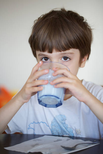 istock Boy is taking his breakfast a glass of warm milk with oat biscuits. 925697480