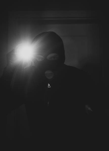 istock Thief wearing mask with a flashlight in the house. 925697644