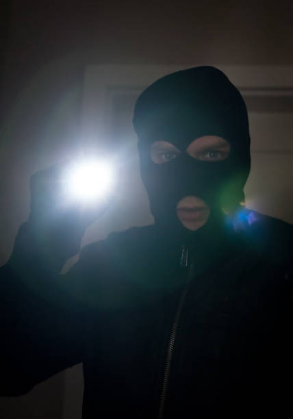 istock Thief wearing mask with a flashlight in the house. 925697652